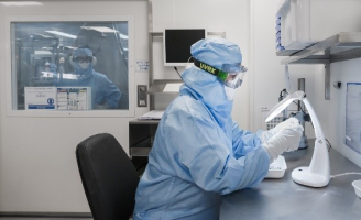 Une opératrice en équipement pour salle blanche analyse un composant pour vérifier sa qualité